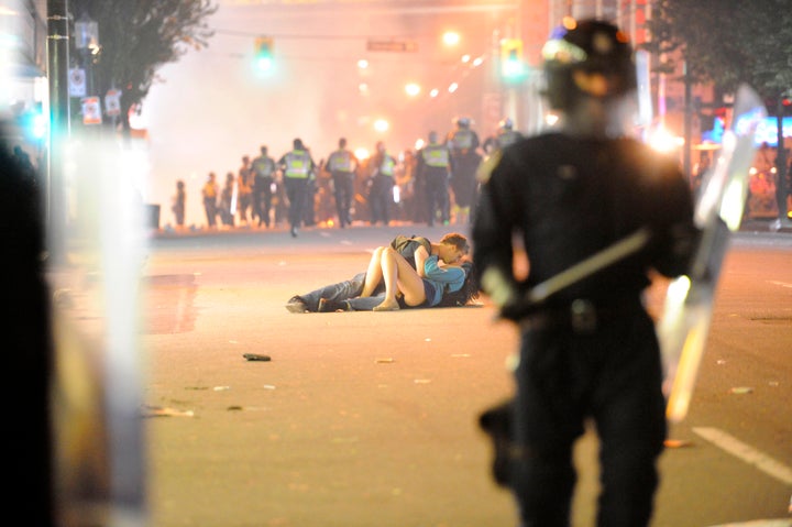 Riot police walk in the street as a couple kiss on June 15, 2011 in Vancouver, Canada.