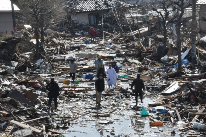 東日本大震災が発生した翌日、がれきの中を歩いて避難する住民＝2011年3月12日午前、宮城県名取市。朝日新聞社撮影