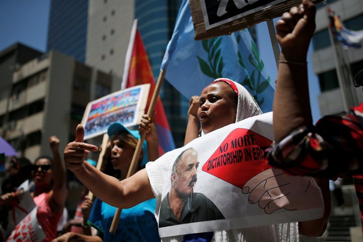 An Eritrean refugee holds a placard depicting Eritrea's President Isaias Afwerki during a demonstration in support of a UN report that accused Eritrean leaders of committing crimes against humanity