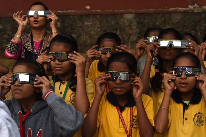 School students use solar filter glasses to view the solar eclipse at a school in Mumbai. 