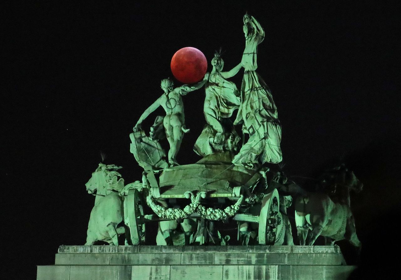 Το φεγγάρι ανάμεσα σε ένα γλυπτό στο Σενκαντενέρ, κατά τη διάρκεια ολικής έκλειψης σελήνης, γνωστής ως «Super Moon Wolf Moon» στις Βρυξέλλες, στις 21 Ιανουαρίου 2019.