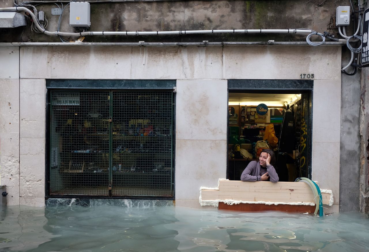 Μια γυναίκα κάθεται στην πόρτα του καταστήματός της, σε μια ακόμη πλημμύρα της Βενετίας, Ιταλία, 17 Νοεμβρίου 2019.