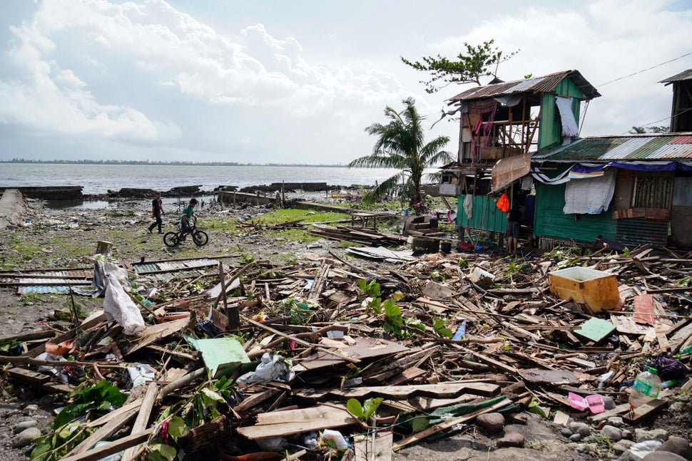 Residents walk past a house damaged during Typhoon Phanfone in Tacloban, Leyte province in the central Philippines on Decembe