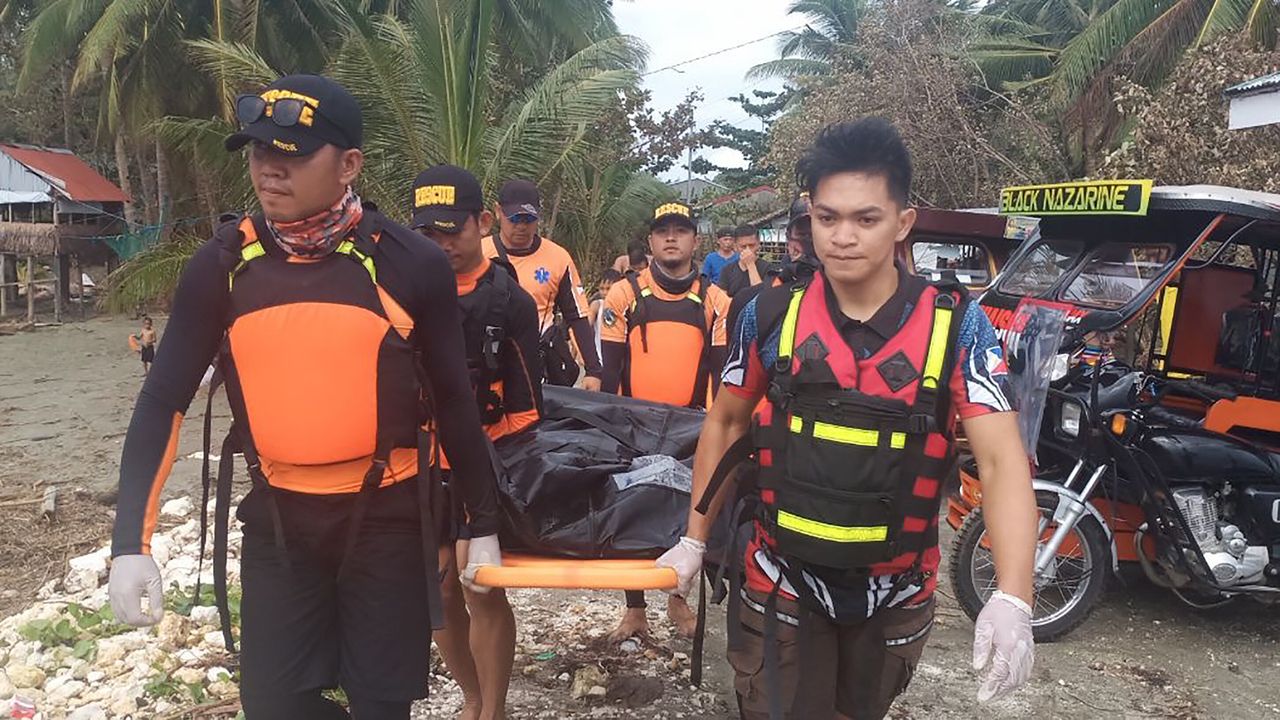 Rescuers carry a body, believed to be one of several fishermen who went missing at the height of Typhoon Phanfone.