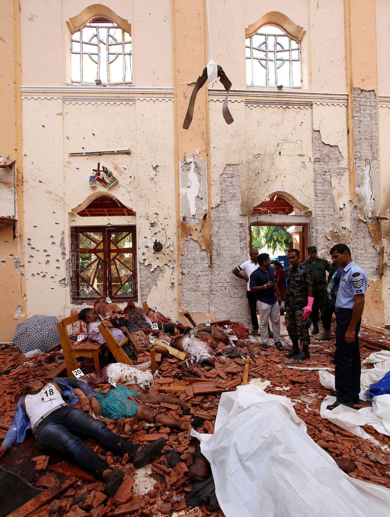 Αστυνομικοί σκέκονται δίπλα από νεκρούς μετά από έκρηξη βόμβας σε εκκλησία στη Σρι Λάνκα στις 21 Απριλίου 2019.