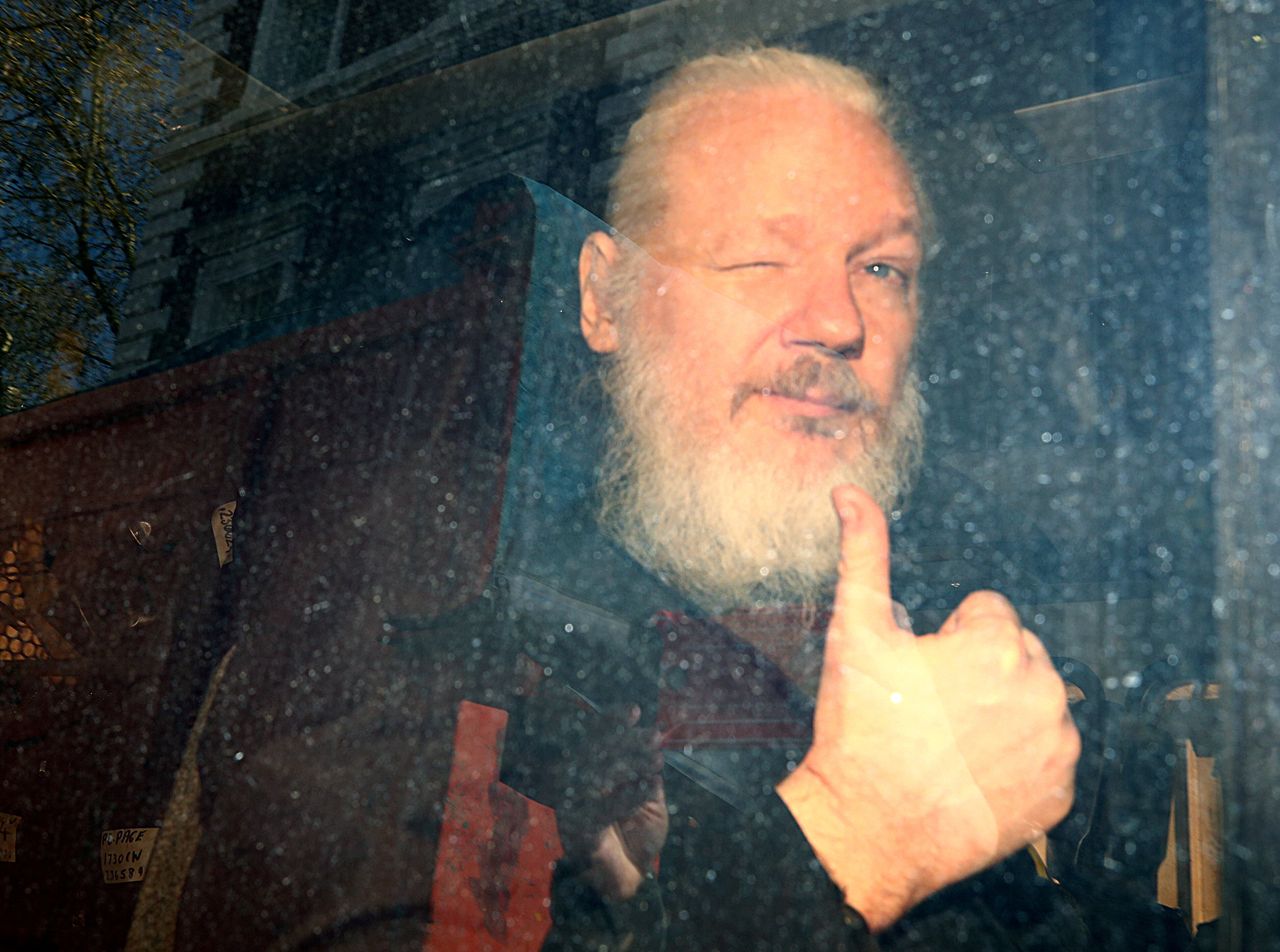 Ο ιδρυτής του WikiLeaks, Τζούλιαν Ασάνζ φτάνει στο δικαστήριο του Γουέστμινστερ, μετά τη σύλληψή του στο Λονδίνο στις 11 Απριλίου 2019. Ο φωτογράφος θυμάται:: «Περιμέναμε τον Τζούλιαν Ασάνζ να εγκαταλείψει την πρεσβεία του Εκουαδόρ εδώ και επτά χρόνια. Κάθε τόσο υπήρχε μια φήμη ότι έφευγε και εμείς προσπαθούσαμε να φτάσουμε στο Knightsbridge (τη γειτονιά όπου βρίσκεται η πρεσβεία), αλλά τίποτα... Όταν έσκασε η είδηση ότι ο Ασάνζ είχε τεθεί υπό κράτηση βρισκόμουν στην Downing Street. Ενώ ο συνάδελφός του Reuters πήρε μια αποκλειστική εικόνα του να φύγει από το αστυνομικό τμήμα και μου είπε ότι ο Ασάνζ βρισκόταν στο δεύτερο βαν της συνοδείας. Όταν τα αστυνομικά βαν έφθασαν επικράτησε πανδαιμόνιο. Οι φωτογράφοι και τα τηλεοπτικά συνεργεία προσπαθούσαν να πάμε μπροστά και οι αστυνομικού μας απωθούσαν. Ένας αστυνομικός ερχόταν προς το μέρος μου. Έσπρωξα προς τα αριστερά και έβγαλα μερικές φωτογραφίες. Για να είμαι ειλικρινής, ήμουν έκπληκτος που κατάφερα να τραβήξω αυτή τη φωτογραφία. Το να βγάζεις σε φιμέ τζάμι είναι δύσκολο. Θα έπρεπε να φέρεις τον φακό σας πιο κοντά γίνεται στο τζάμι του κινούμενου αυτοκινήτου, και να βγάλεις με φλας για να φωτίσεις μέσα από το τζάμι. Μου είπαν ότι η εικόνα θυμίζει ελαιογραφία. Αυτό οφείλεται εν μέρει στο χρώμα του φιμέ τζαμιού και εν μέρει επειδή η εικόνα δεν είναι εντελώς σταθερή.