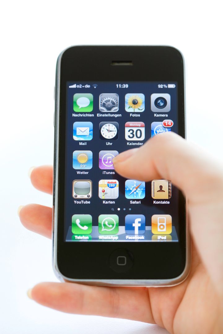 hand holding iPhone 3 typing on home screen