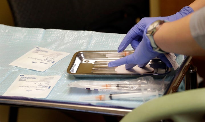 A health care worker prepares syringes, including a vaccine for measles, mumps and rubella, for a child's inoculations in Seattle.