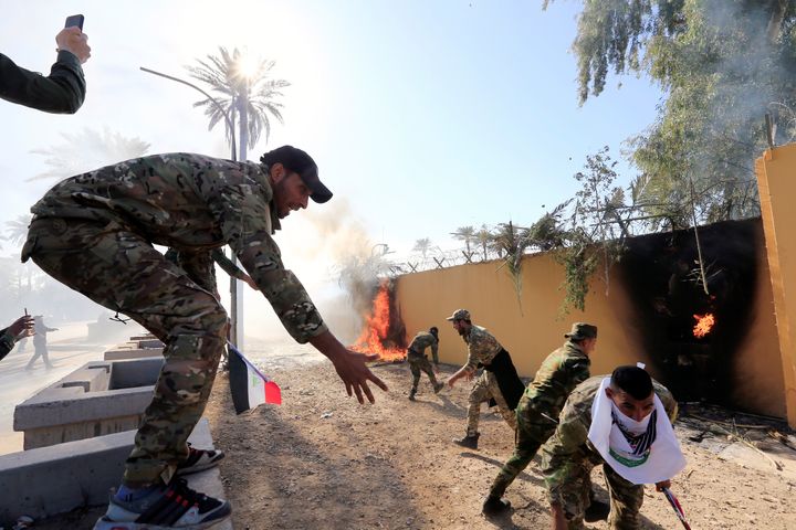Hashd al-Shaabi (paramilitary forces) fighters set fire on the US embassy wall to condemn air strikes on their bases, in Baghdad, Iraq, on December 31