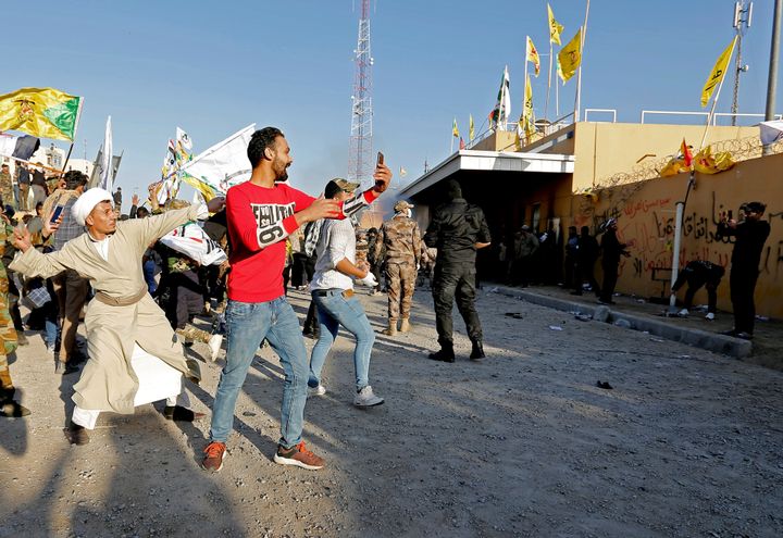 Demonstrators and militia fighters throw stones toward the U.S. Embassy in Baghdad on Dec. 31 during a protest to condemn airstrikes on bases belonging to Hashd al-Shaabi.