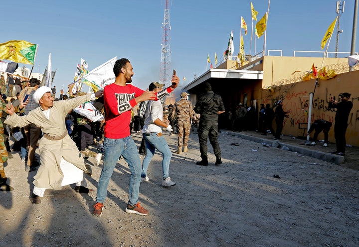 Demonstrators and militia fighters throw stones toward the U.S. Embassy in Baghdad on Dec. 31 during a protest to condemn airstrikes on bases belonging to Hashd al-Shaabi.