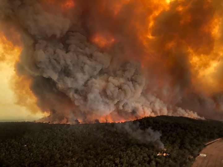 Wildfires rage under plumes of smoke in Bairnsdale, Australia, on Monday. Thousands of tourists fled Australia's wildfire-ravaged eastern coast Thursday ahead of worsening conditions as the military started to evacuate people trapped on the shore further south.