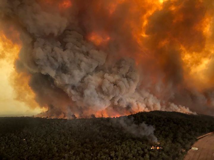 Wildfires rage under plumes of smoke in Bairnsdale, Australia, on Monday. Thousands of tourists fled Australia's wildfire-rav