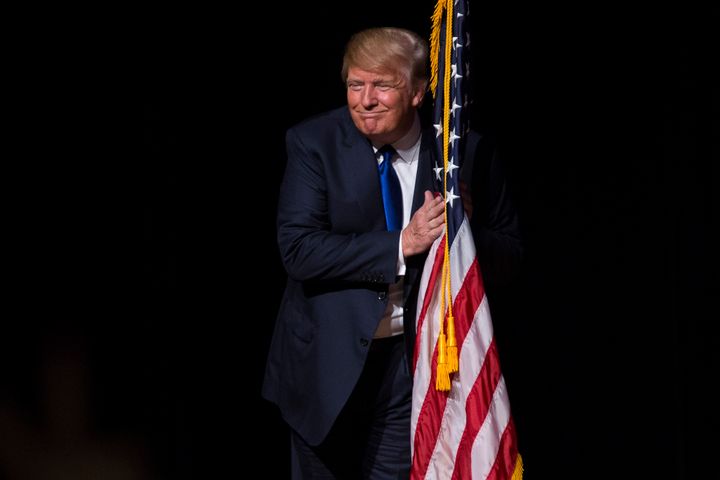 DERRY, NH - AUGUST 19: U.S. Republican presidential candidate Donald Trump hugs an American flag as he takes the stage for a town hall meeting in Derry, New Hampshire, August 19, 2015. (Keith Bedford/The Boston Globe via Getty Images)