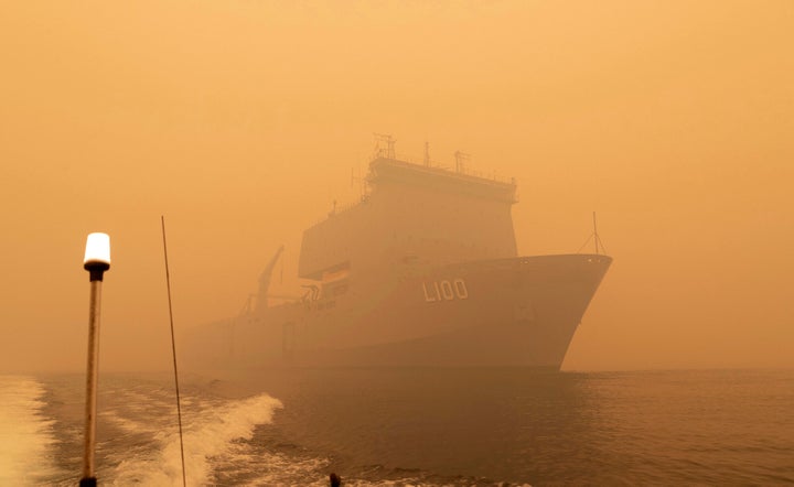 In this photo released and taken Jan. 2, 2020, by the Australian Department of Defense, the HMAS Choules sails off the coast of Mallacoota, Victoria to supply support to people cut off by bush fires. Navy ships plucked hundreds of people from beaches and tens of thousands were urged to flee before hot weather and strong winds in the forecast worsen Australia's already-devastating wildfires. (Australian Department of Defense via AP)