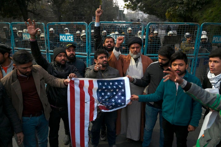 Protesters in Lahore, Pakistan, hold a burned American flag and shout slogans near the U.S. consulate after the assassination of Soleimani in Iraq.