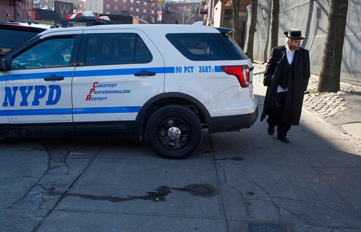 A Hasidic man walks past a police patrol car on Dec. 12 in the Williamsburg neighborhood of Brooklyn. Hasidic leaders have asked for a stronger police presence.