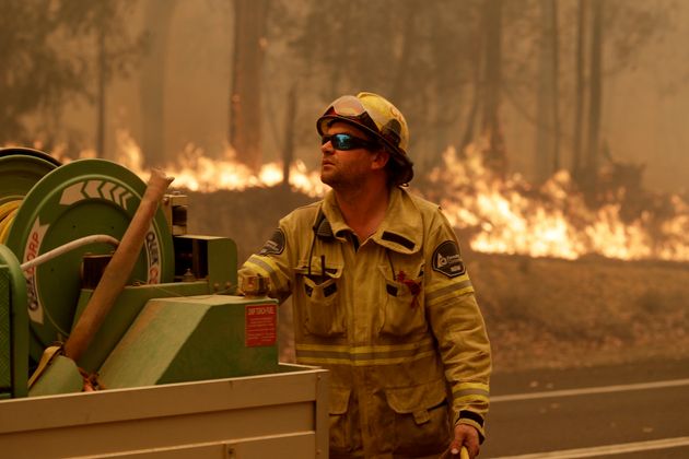 A Forest Corporation worker manages a fire hose as he battles a fire near Moruya, Australia, Saturday,...