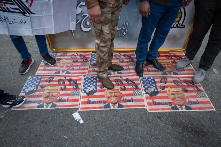 Mourners step over a U.S. flags with pictures of President Donald Trump during the funeral procession for Iran's top general Qassem Soleimani.