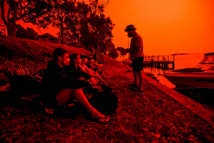 A parent assures their children that fires are not headed toward the town as the skies above turn red during the day on Jan. 4 in Mallacoota, Australia. Many parents with young families were unable to get their children out on the evacuation because they only allowed school-aged children and above to evacuate by boat. People in the Foreshore Caravan Park are staying through what will be a day of severe fire conditions with large fires still burning out of control to the north of the town. A change in south-westerly winds has been sparking fire activity in the area.