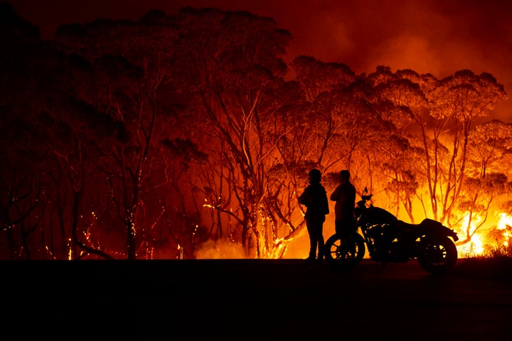 Residents look on as flames burn through bush on Jan. 4 in Lake Tabourie, Australia. A state of emergency has been declared across NSW with dangerous fire conditions forecast for Saturday, as more than 140 bushfires continue to burn. There have been eight confirmed deaths in NSW since Dec. 30. Some 1,365 homes have been lost, while 3.6 million hectares have been burnt this fire season. 