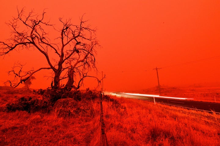 A long exposure picture shows a car commuting on a road as the sky turns red from smoke of the Snowy Valley bushfire on the outskirts of Cooma on Jan. 4.