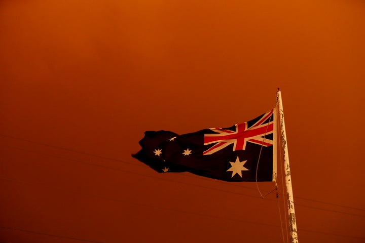 The Australia flag flies under red skies from the fires on Jan. 4 in Bruthen, Australia. Two people are dead and 28 remain missing following bushfires across the East Gippsland area, with Victorian premier Daniel Andrews declaring a state of disaster in the region. Thousands of people remain stranded in the coastal town of Mallacoota and are being evacuated by navy ships to Melbourne.