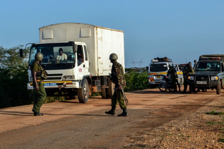 Kenyan police officers check vehicles on a road after a bus, traveling from the coastal region of Lamu to the town of Malindi