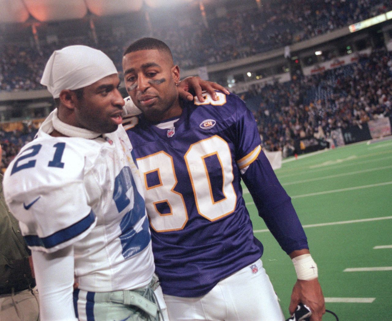 Sanders of the Dallas Cowboys (left) and Minnesota Vikings wide receiver Cris Carter greet each other following a Vikings playoff victory in 1999.