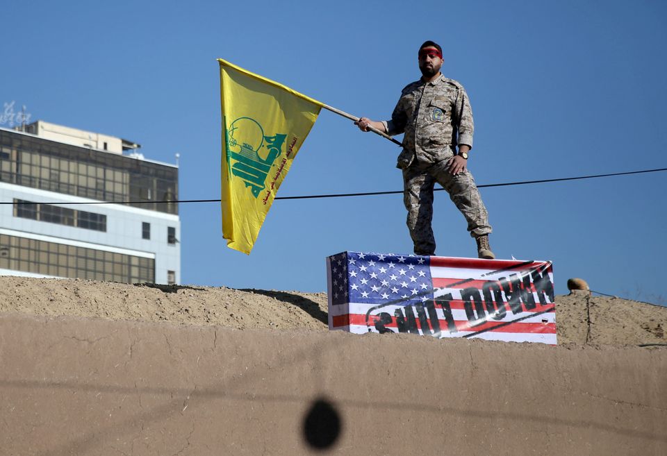 An Iranian guard holds a Hezbollah flag during a funeral procession and burial for Iranian Major-General Qassem Soleimani/