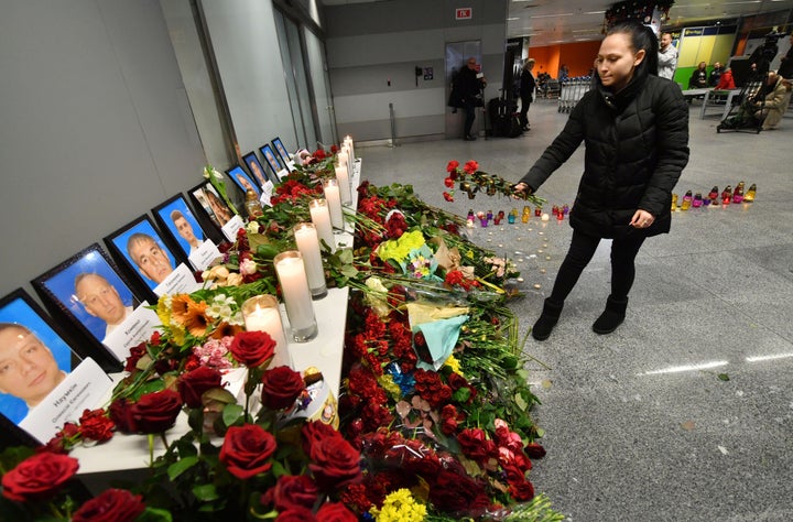 Una mujer coloca flores ante las fotos de los pasajeros, en el aeropuerto de Boryspil, en Kiev.