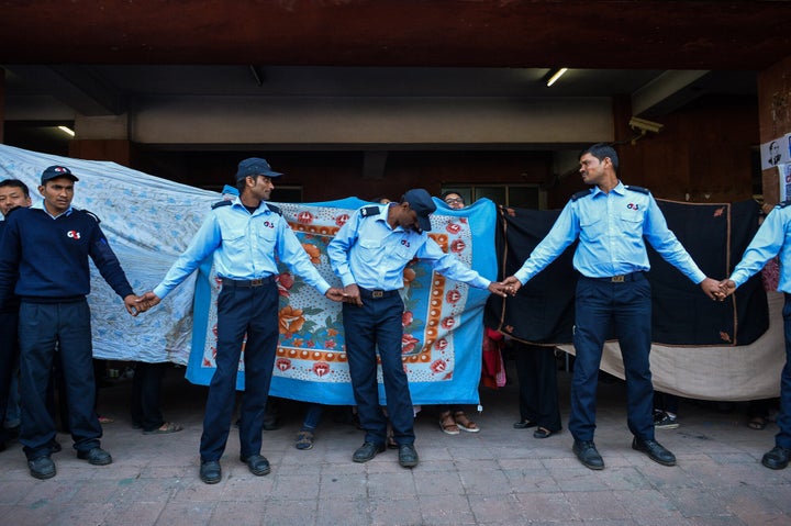 A February 2016 photo of G4S security guards standing in front of former student activist Umar Khalid (unseen) as other students hold up sheets to shield him at JNU.