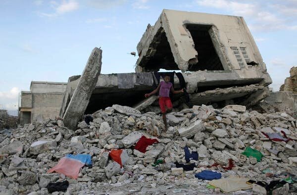 Quelques mois après le tremblement de terre, une fillette marche sur des débris alors qu’elle utilise la structure d’un bâtiment endommagé, à Port-au-Prince, pour sécher à l’air libre des vêtements.