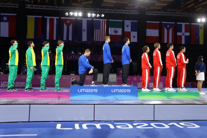 Fencing gold medalist Race Imboden of the United States takes a knee during the national anthem at the Pan American Games on Aug. 9, 2019, in Lima, Peru.