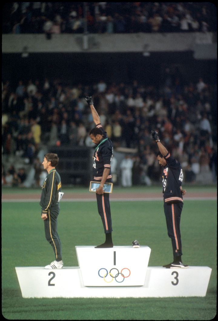 メキシコオリンピックで拳を突き上げて抗議をした、トミー・スミス選手（中央）とジョン・カーロス選手（右）