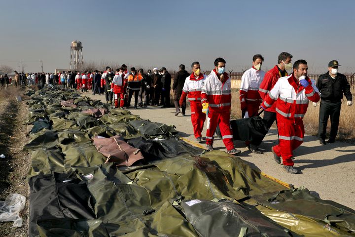 Rescue workers carry the body of a victim of a Ukrainian plane crash in Shahedshahr, southwest of the capital Tehran, Iran, Wednesday.
