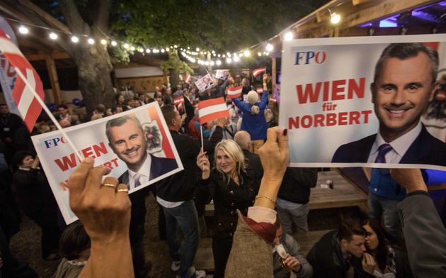 Supporters of the far-right Freedom Party hold campaign posters featuring their party leader Norbert...