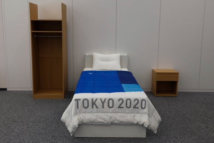 A set of bedroom furniture, including a cardboard bed, is photographed in a display room showing furniture for the Tokyo 2020