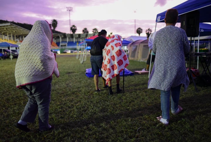 People get up after spending the night in a baseball stadium amid aftershocks and without electricity after the 6.4 magnitude earthquake in Guayanilla, Puerto Rico, at sunrise Friday, Jan. 10, 2020.