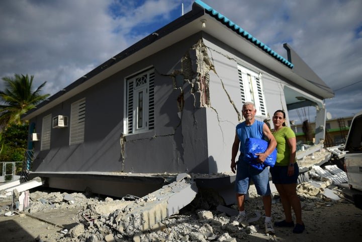 67 year-old William Mercuchi, center, and his daughter Joan pose for photos in front of their house that collapsed after the previous day's magnitude 6.4 earthquake in Yauco, Puerto Rico, Wednesday, Jan. 8, 2020.