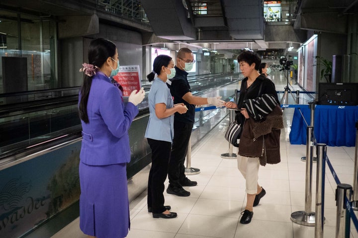 Public Health officials hand out disease monitoring information after performing thermal scans on passengers arriving from Wuhan, China at Suvarnabumi Airport.