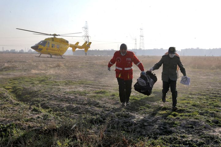 Rescue workers carry items retrieved from the scene where a Ukrainian plane crashed in Shahedshahr, southwest of the capital Tehran, Iran, Wednesday, Jan. 8, 2020. 