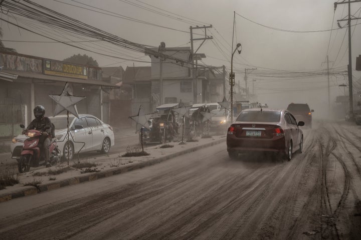 Los automovilistas conducen a través de un camino cubierto de cenizas volcánicas de la erupción del volcán Taal en Lemery, provincia de Batangas, Filipinas