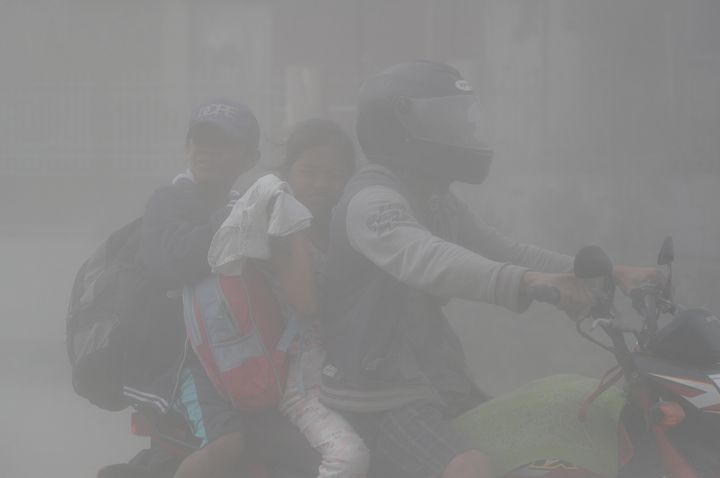 A family rides through clouds of ash as they evacuate to safer ground from the area near Taal