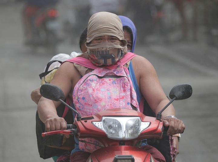 A man rides his motorcycle along an ash-covered road as they evacuate the area near the Taal volcano 