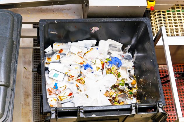 Leftovers of airline food in a large waste container from in-flight service.