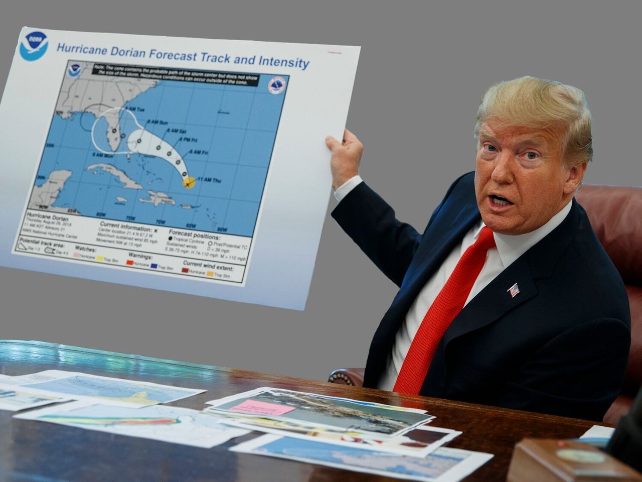Trump holds a Hurricane Dorian forecast tracking chart -- adjusted by a Sharpie -- as he talks with reporters in the White House Oval Office.
