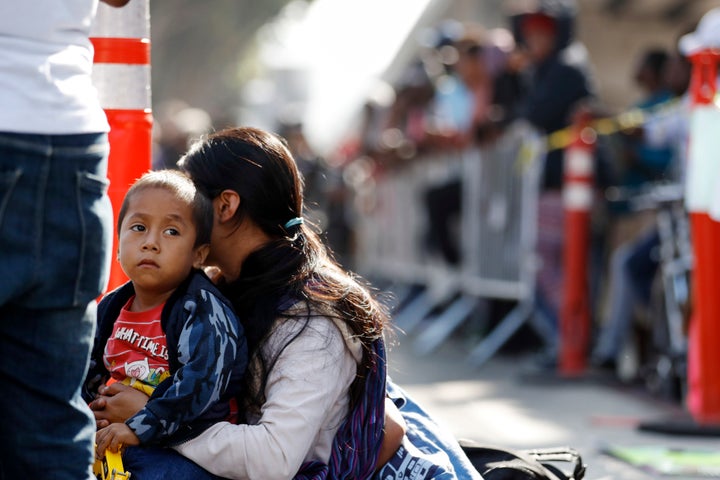 A woman sits with her sons as they wait to apply for asylum in the United States along the border, Tuesday, July 16, 2019, in
