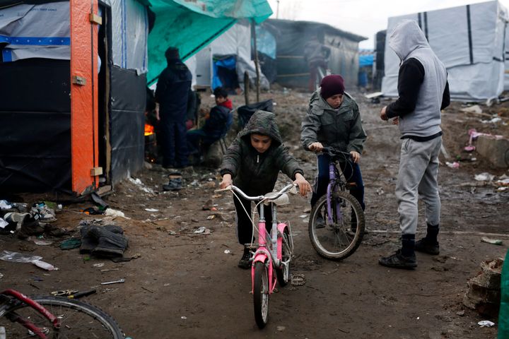 Afghan children ride their bicycles in a makeshift migrants camp near Calais in 2016