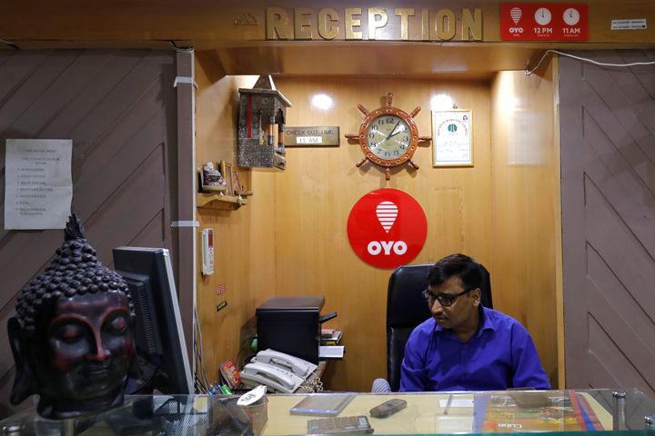 An employee sits next to the logo of OYO, at the reception of a hotel in New Delhi, India, September 25, 2018. REUTERS/Anushree Fadnavis